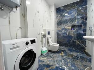 a bathroom with a washing machine and a toilet at Saranda Terraces Apartment Rentals in Sarandë +37 photos