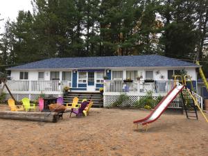 a playground in front of a house with a slide at Wu Wu's Cabins in Wasaga Beach