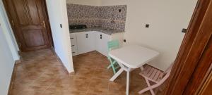uma pequena cozinha com uma mesa branca e cadeiras em Page et montagne chez Ben&Edd em Alcácer-Ceguer