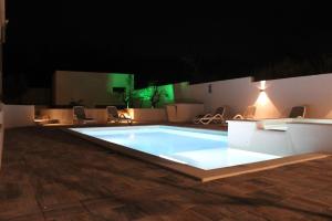 una piscina por la noche con sillas alrededor en Holiday House emjalemi en Pula