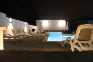 a group of chairs and a swimming pool at night at Holiday House emjalemi in Pula