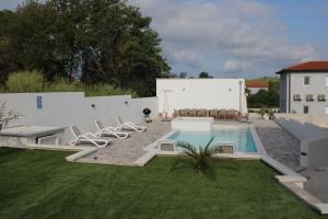 a backyard with a swimming pool with chairs next to a building at Holiday House emjalemi in Pula