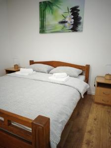 sypialnia z dużym drewnianym łóżkiem z białą pościelą w obiekcie Apartman Aura Prijedor w mieście Prijedor
