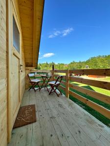 un porche con 2 mesas de picnic y una valla en Green River - robinzonski kamp, en Duga Resa