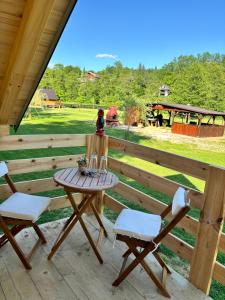 a table and chairs on a porch with a view of a field at Green River - robinzonski kamp in Duga Resa