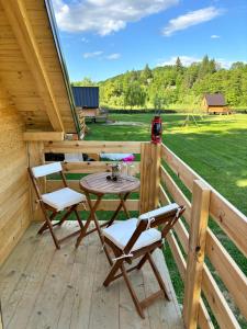 una terraza de madera con mesa y 2 sillas en Green River - robinzonski kamp en Duga Resa