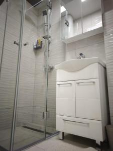 La salle de bains est pourvue d'un lavabo et d'une douche. dans l'établissement Apartman Aura Prijedor, à Prijedor
