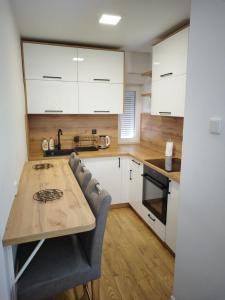 a kitchen with white cabinets and a wooden table at Apartman Aura Prijedor in Prijedor