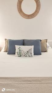 un letto bianco con cuscini e uno specchio a parete di oasismarverdemar a Corralejo