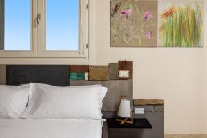 a bedroom with a bed with white sheets and a window at Fiore di Vendicari B&B - Sicilian Charme, Lemon Grove and Sea in Noto