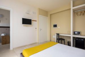 a bedroom with a bed and a desk with a television at Fiore di Vendicari B&B - Sicilian Charme, Lemon Grove and Sea in Noto