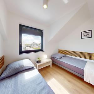 two beds in a bedroom with a window at Apartamenty SOLEIL in Sarbinowo