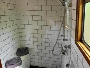 uma casa de banho com um chuveiro com azulejos brancos em Unique Canal Boat in London Centre for Family & Friends em Londres