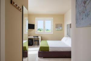 a bedroom with a bed and a desk and a window at Fiore di Vendicari B&B - Sicilian Charme, Lemon Grove and Sea in Noto