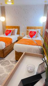 two beds with red pillows in a room at Luxe Smart Home - Basildon Serviced Accommodation - 7 Mins Walk To Basildon Town Centre, Hospital & Train Station in Basildon