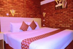 a bedroom with a white bed and a brick wall at Hôtel Saint Jean Leopold in Kigali