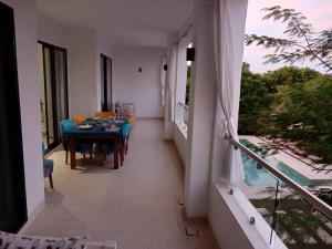 a dining room with a table and chairs and a balcony at Sandbox Apartment 4 Diani Beach Kenya in Ukunda