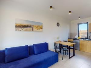 a living room with a blue couch and a table at Apartamenty SOLEIL in Sarbinowo