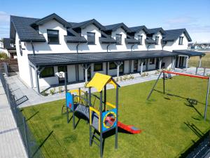 a playground in front of a house at Apartamenty SOLEIL in Sarbinowo
