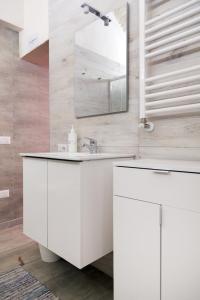 ein weißes Badezimmer mit einem Waschbecken und einem Spiegel in der Unterkunft Antico Lamione in Matera