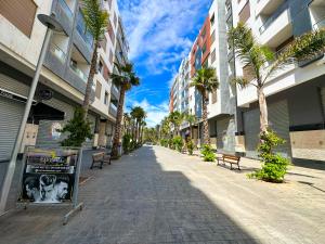 een straat met banken en palmbomen in een gebouw bij Appartement de luxe au Parc au centre pres de la plage in Mohammedia