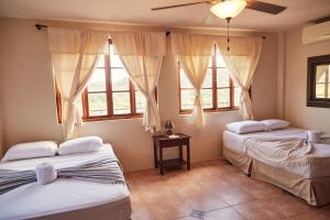 two beds in a room with two windows at Beachside stay at Villa ViYarte in San Juan del Sur
