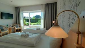 a hotel room with two beds and a lamp at Ostseehotel Kappeln by team SchleiFee in Kappeln
