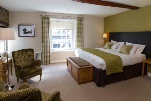 a hotel room with a large bed and a chair at Sun Inn in Kirkby Lonsdale
