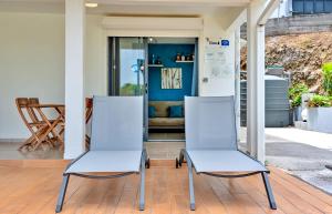 two white chairs sitting on the porch of a house at La Perle du Cap in Case-Pilote