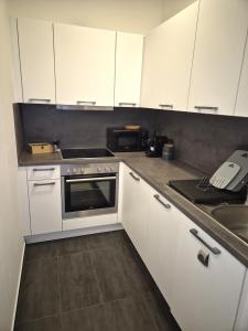 a kitchen with white cabinets and a stove and a sink at Ferienwohnung Bobingen in Bobingen +8 photos