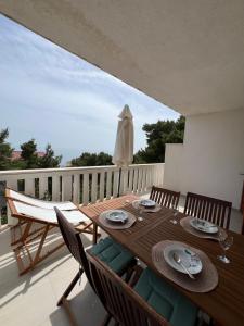 a wooden table and chairs on a balcony with an umbrella at Apartmani Vranković in Sveta Nedelja