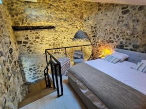 a bedroom with a bed and a stone wall at La Romarine in Chauzon