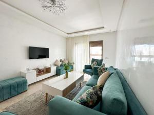 een woonkamer met een blauwe bank en een tv bij Appartement de luxe au Parc au centre pres de la plage in Mohammedia