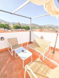 贝莱斯德韦瑙达利亚Pura Vida - Terraza, Piscina, Playa 15mn, Sierra的带桌椅和遮阳伞的阳台