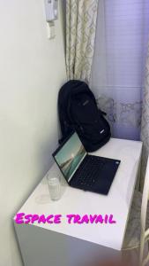 La Perle du Sahel avec clé personnel du portail في نيامي: يوجد جهاز كمبيوتر محمول على طاولة مع حقيبة ظهر