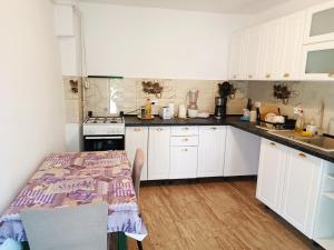a kitchen with white cabinets and a table at Casa Bunicilor in Cisnădie