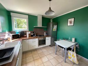 a kitchen with green walls and a table in it at Maison Mboa in Fouesnant