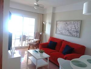 ein Wohnzimmer mit einem roten Sofa und einem Tisch in der Unterkunft Apartamento Con Vistas en Nerja in Nerja