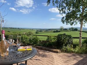a table with wine glasses and a book on it at Betula Views in Newent