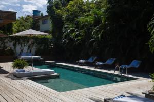 een zwembad met 2 stoelen en een parasol bij Santa Fe Casas Hotel Trancoso in Trancoso