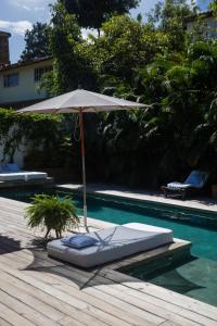 een parasol op een terras naast een zwembad bij Santa Fe Casas Hotel Trancoso in Trancoso