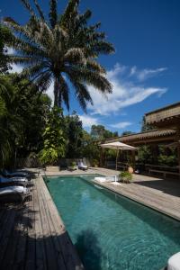een zwembad met een palmboom op de achtergrond bij Santa Fe Casas Hotel Trancoso in Trancoso