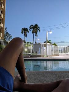 une femme assise à côté d'une piscine dans l'établissement Spacious gated 2 bed 2 bath with pool, à San Juan