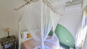 a bedroom with a canopy bed with white curtains at Vila Pitanga Trancoso in Trancoso