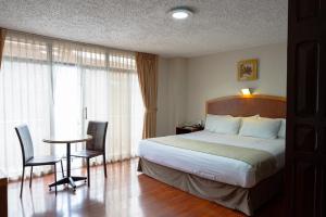 Habitación de hotel con cama, mesa y sillas en Hotel Santa Monica en Cuenca