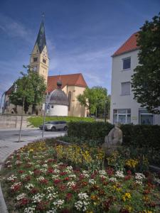 a building with a clock tower and a flower garden at Ferienwohnung Bobingen in Bobingen