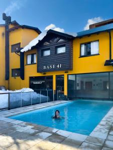 eine Person, die in einem Schwimmbecken vor einem Gebäude schwimmt in der Unterkunft Complejo Base 41 in San Carlos de Bariloche