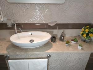 baño con lavabo blanco y flores en una encimera en Luna Chiara Residence en Tusa