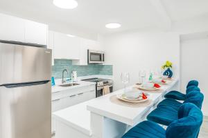 a white kitchen with blue chairs and a table at Newly Renovated 2 Bedroom Condo, 1 Block to Waikiki Beach, Free Parking in Honolulu