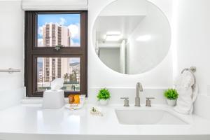 a white bathroom with a sink and a mirror at Newly Renovated 2 Bedroom Condo, 1 Block to Waikiki Beach, Free Parking in Honolulu
